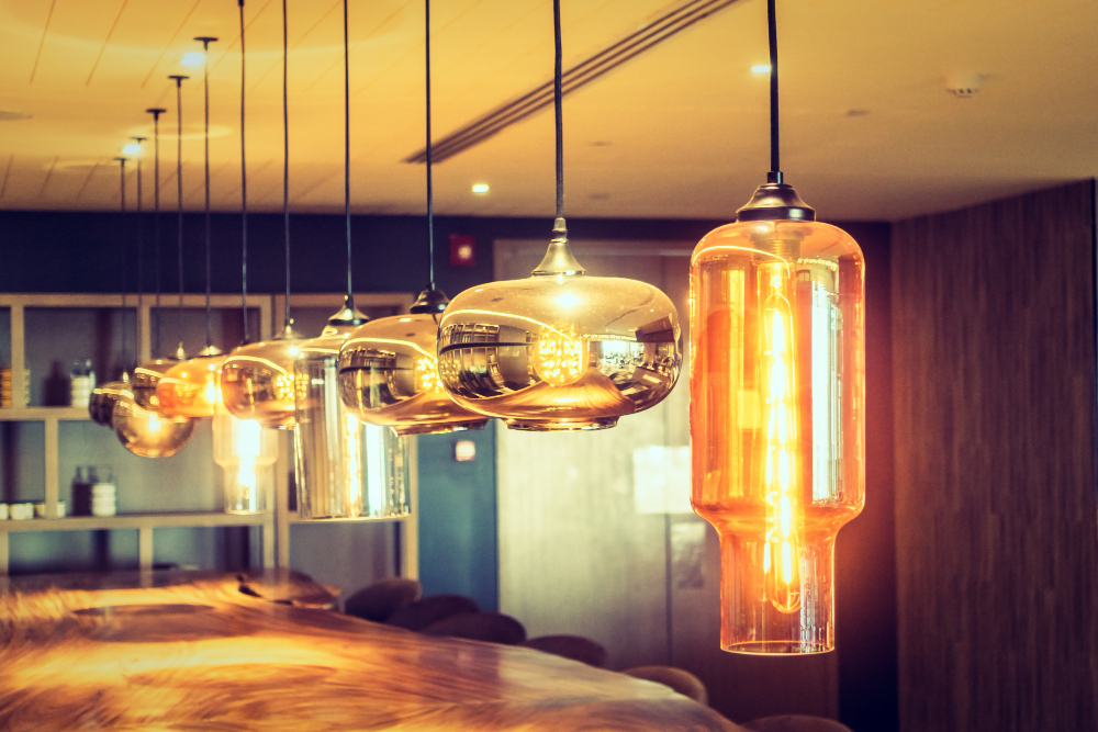 Conjunto de luminárias pendentes modernas com lâmpadas de design em diferentes formatos e tons dourados.